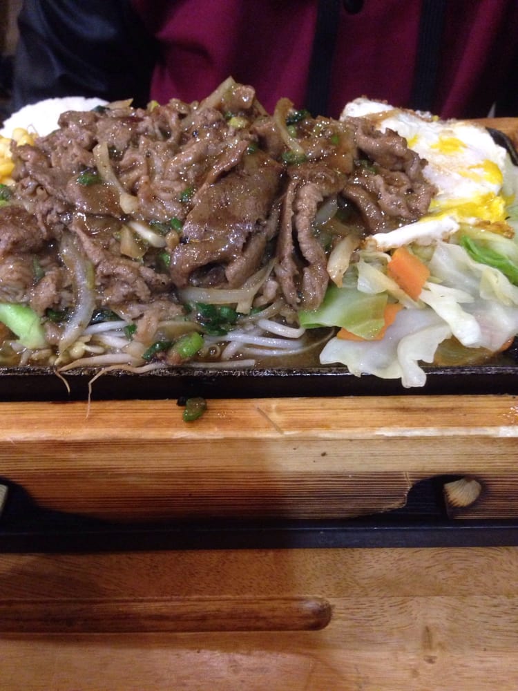 Sliced beef stir-fried with vegetables on a sizzling iron plate